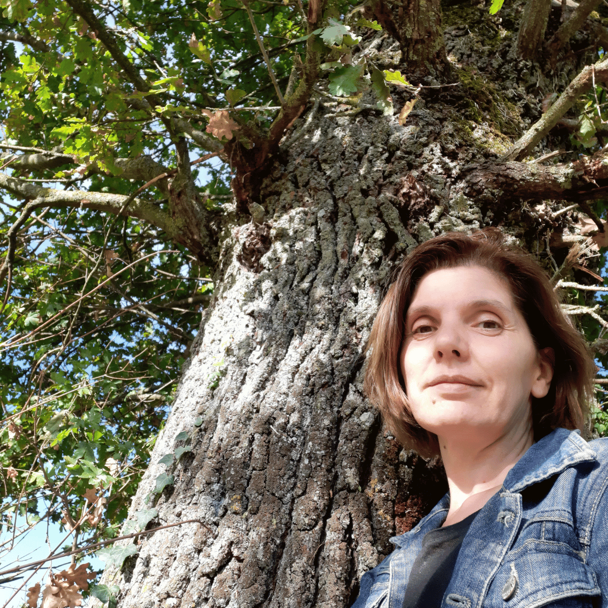 Femme brune à côté d'un arbre