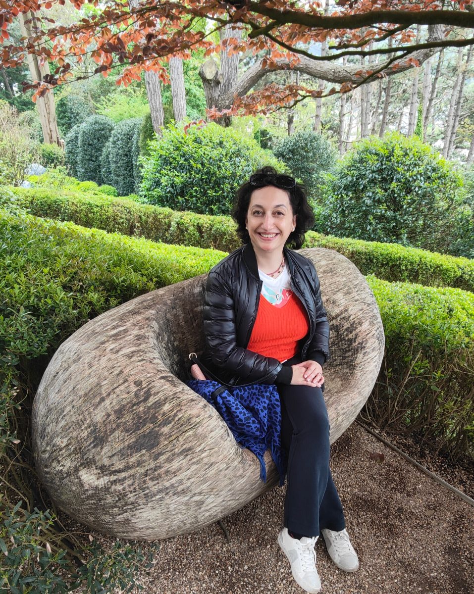 Photo de femme assise sur un banc sous un arbre.